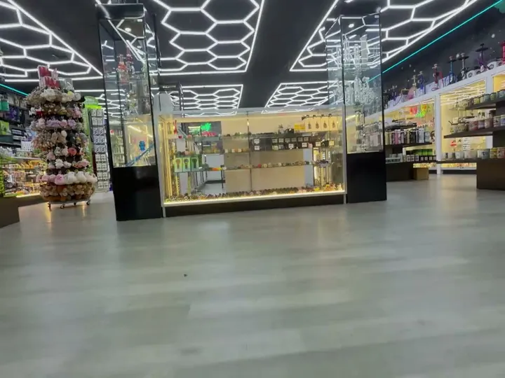 Wide low view across the shop floor to a lit glass counter, glass towers and hexagon ceiling lights