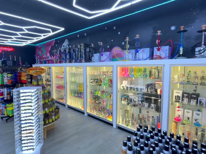 Sock rack, incense stand and lit glass cases with hookahs on top, under hexagon ceiling lights