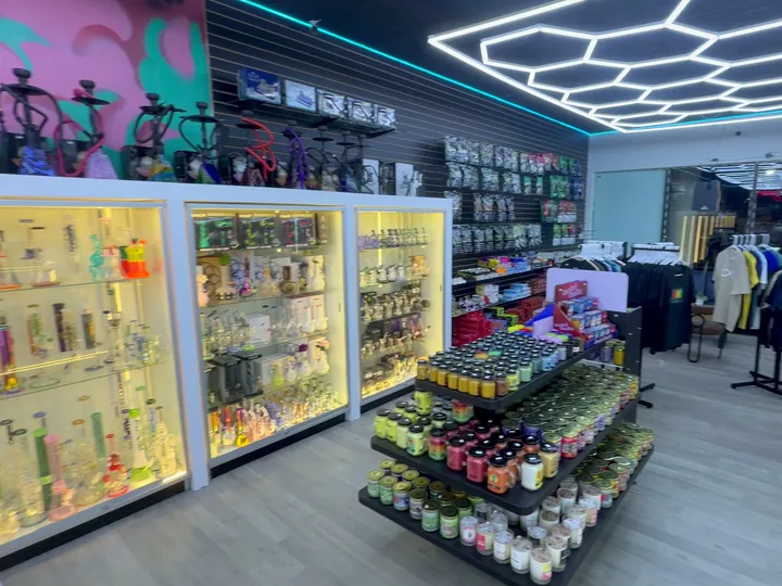 Lit glass cases with hookahs on top, a candle table and a tobacco wall in the back corner of the shop