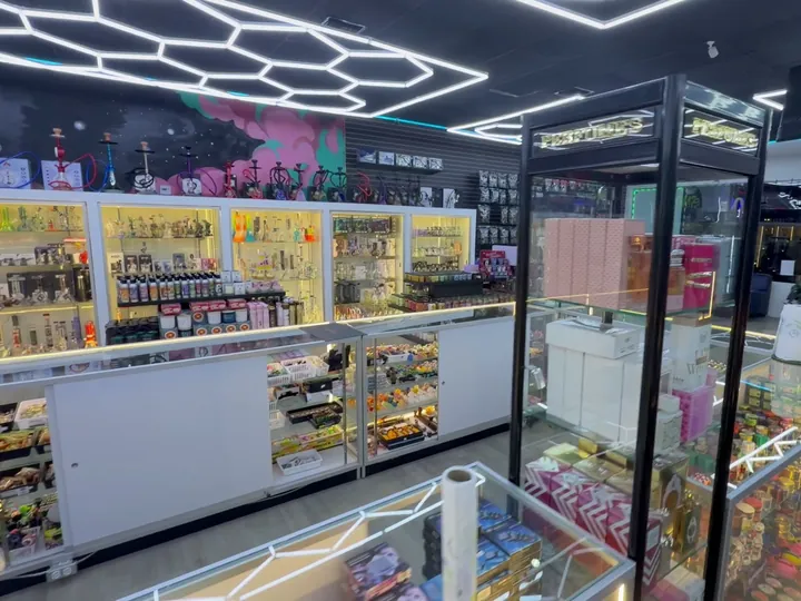 Lit wall cases with hookahs above, a perfume tower and a glass counter under hexagon lights