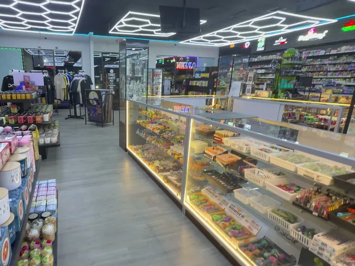 Aisle lined with candles and gifts beside a lit glass counter of hand pipes