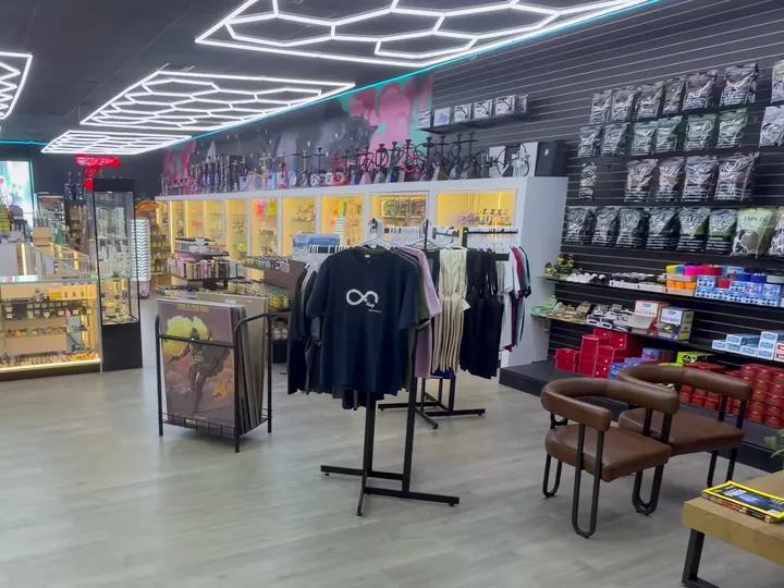 Sales floor with T-shirt racks, a lit glass case and a slatwall of tobacco pouches